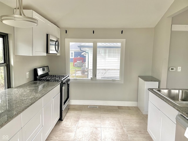 kitchen featuring white cabinets, stainless steel appliances, sink, stone countertops, and hanging light fixtures