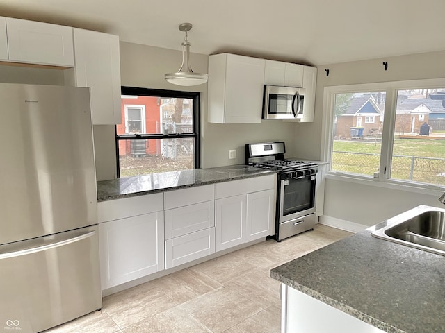 kitchen with stainless steel appliances, pendant lighting, white cabinetry, and sink