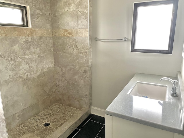 bathroom featuring tile patterned flooring, tiled shower, and vanity