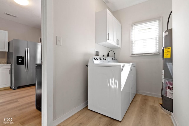 washroom with washer and clothes dryer, water heater, cabinets, and light hardwood / wood-style flooring