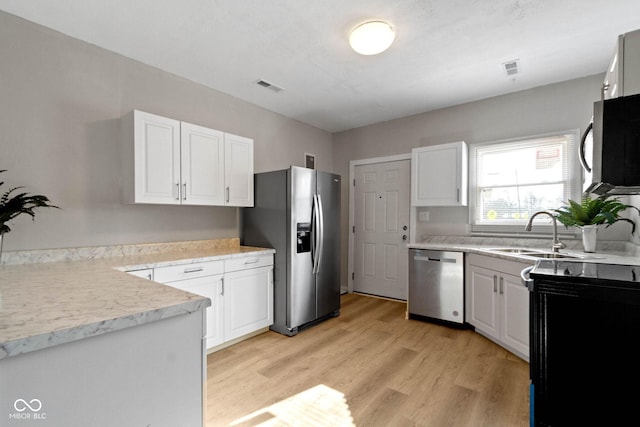 kitchen with sink, white cabinets, light hardwood / wood-style floors, and appliances with stainless steel finishes