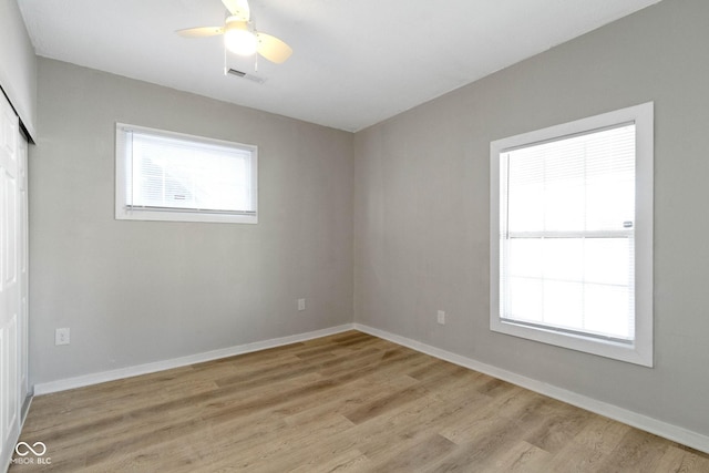 empty room with ceiling fan, a healthy amount of sunlight, and light hardwood / wood-style floors