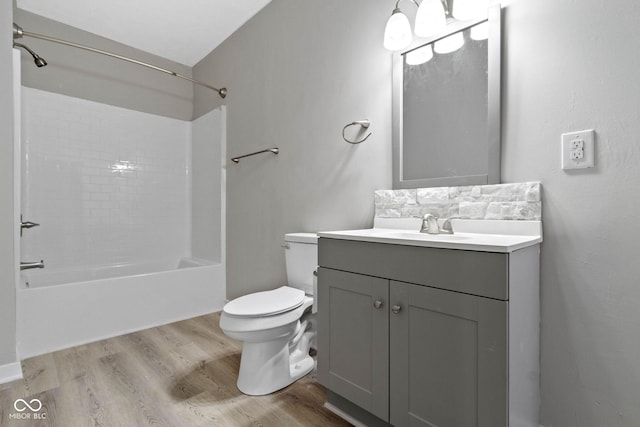 full bathroom with hardwood / wood-style flooring, vanity,  shower combination, and toilet