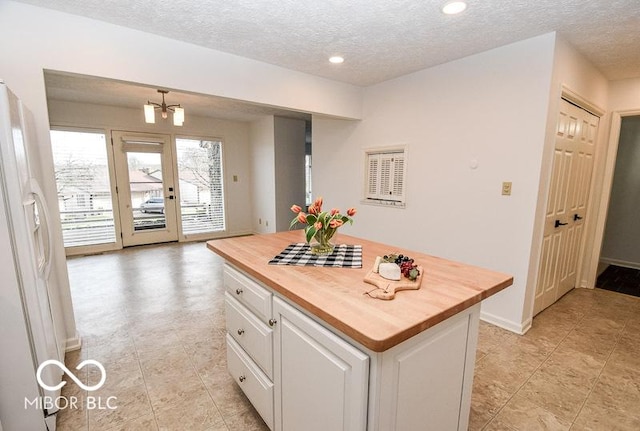 kitchen with wood counters, a textured ceiling, white cabinets, a kitchen island, and white fridge with ice dispenser