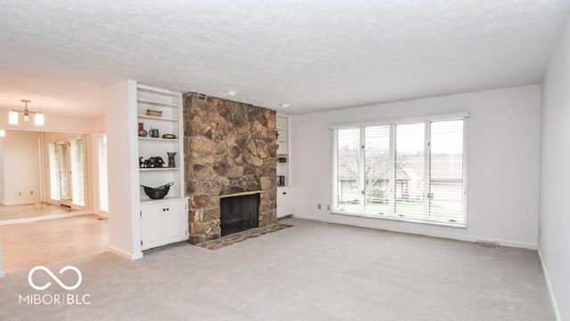 unfurnished living room with light carpet, built in shelves, a textured ceiling, a notable chandelier, and a stone fireplace