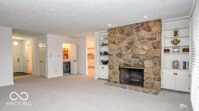 unfurnished living room with built in shelves, a fireplace, light colored carpet, and a textured ceiling