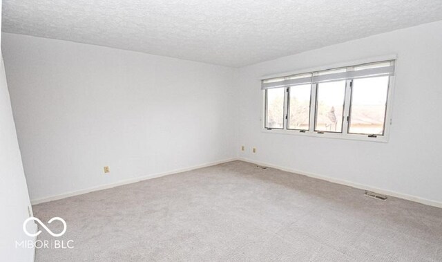 carpeted spare room with a textured ceiling