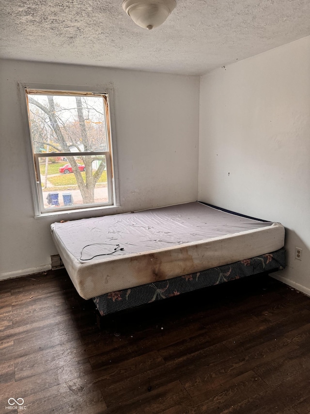 unfurnished bedroom with a textured ceiling and dark hardwood / wood-style floors