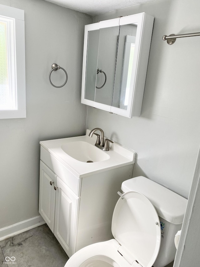 bathroom featuring vanity, concrete flooring, and toilet