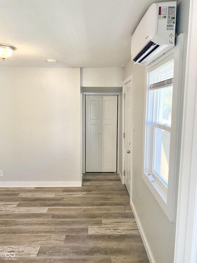 corridor with a wealth of natural light, a wall mounted air conditioner, and hardwood / wood-style flooring