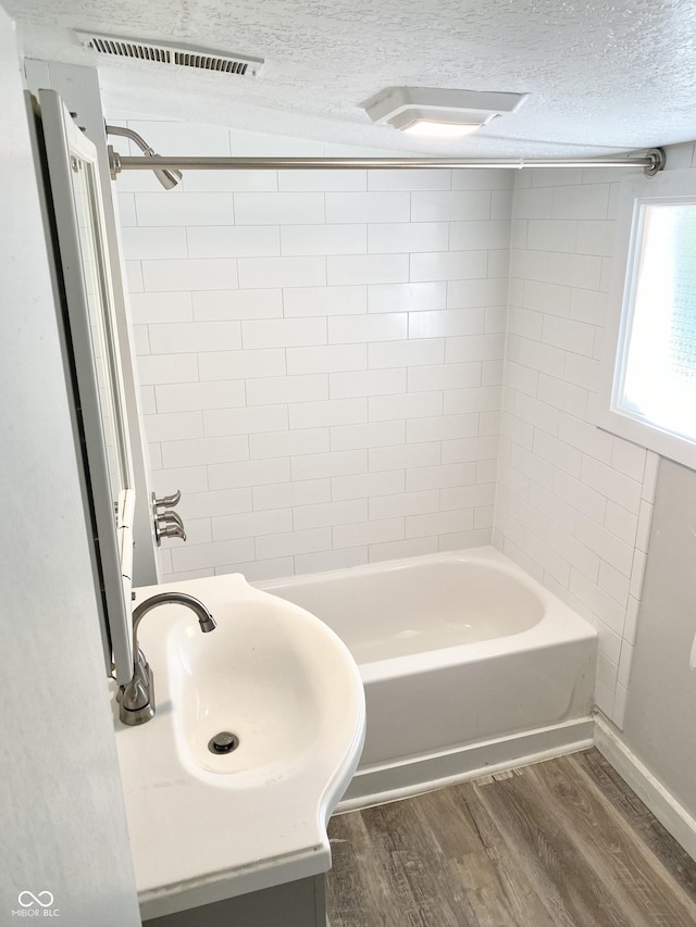 bathroom with sink, tiled shower / bath combo, a textured ceiling, and hardwood / wood-style flooring