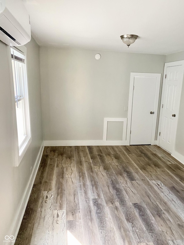 unfurnished room featuring wood-type flooring and a wall unit AC