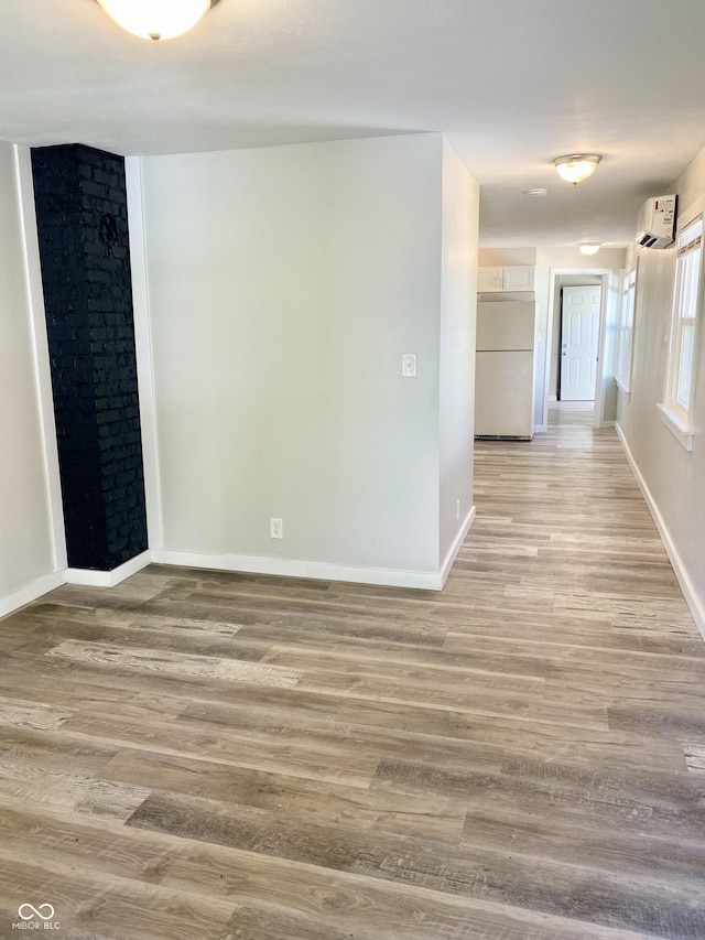 empty room featuring a wall mounted AC and wood-type flooring