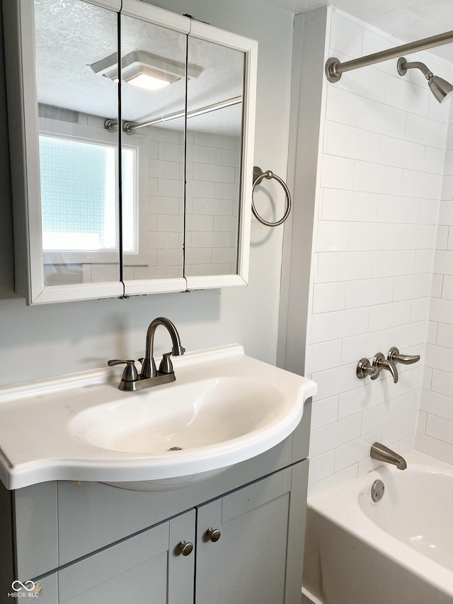 bathroom featuring vanity, a textured ceiling, and tiled shower / bath combo