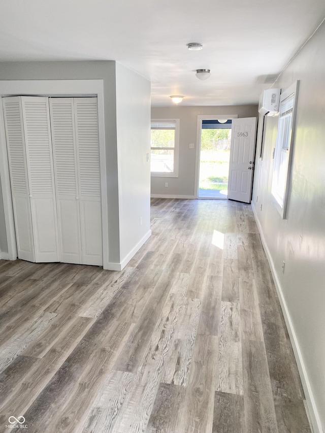 hall with a wall unit AC and wood-type flooring