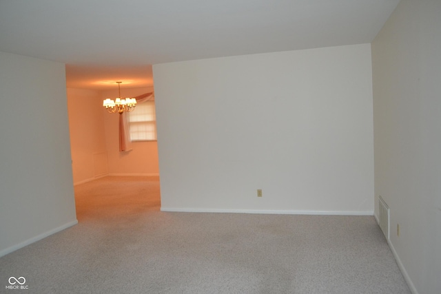 carpeted spare room featuring a notable chandelier