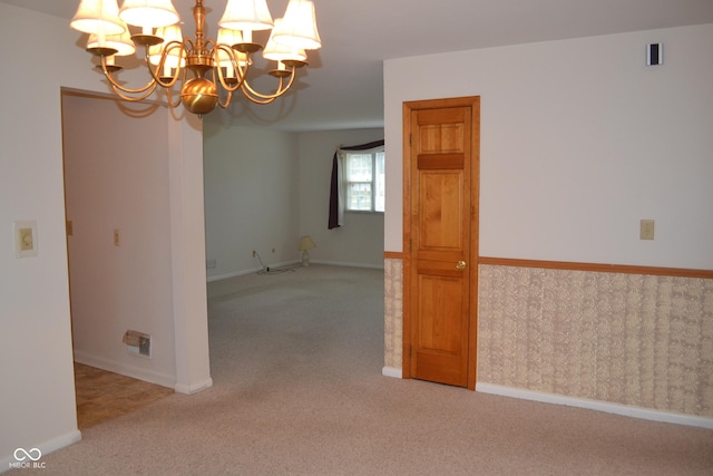 carpeted spare room with a notable chandelier