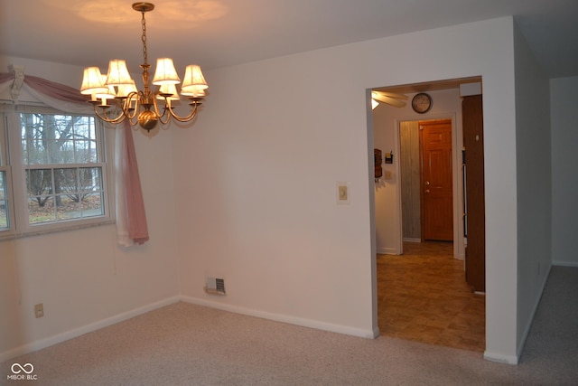 carpeted spare room with a chandelier