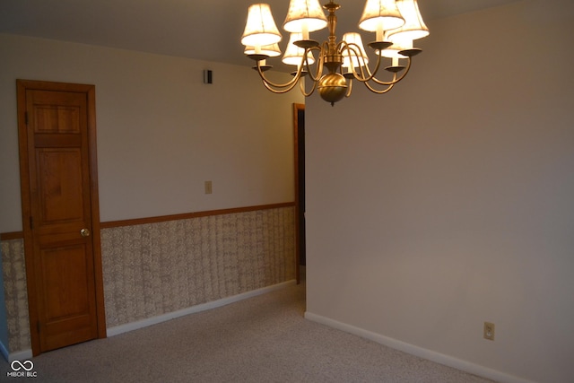 empty room featuring a chandelier and carpet