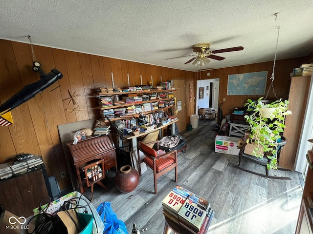 misc room featuring ceiling fan, dark hardwood / wood-style floors, a textured ceiling, and wooden walls