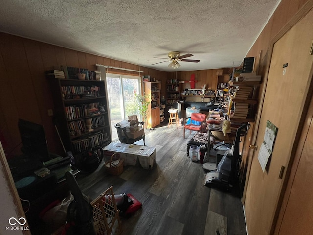 miscellaneous room with a textured ceiling, hardwood / wood-style flooring, ceiling fan, and wood walls