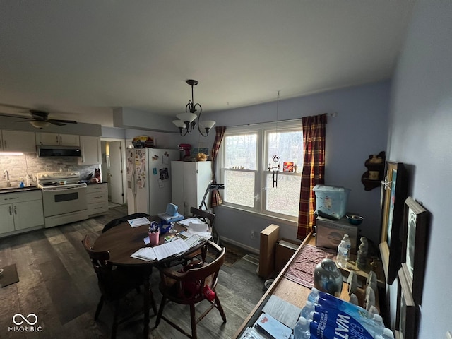 dining area featuring dark hardwood / wood-style flooring, ceiling fan with notable chandelier, and sink