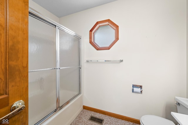 bathroom featuring shower / bath combination with glass door and toilet