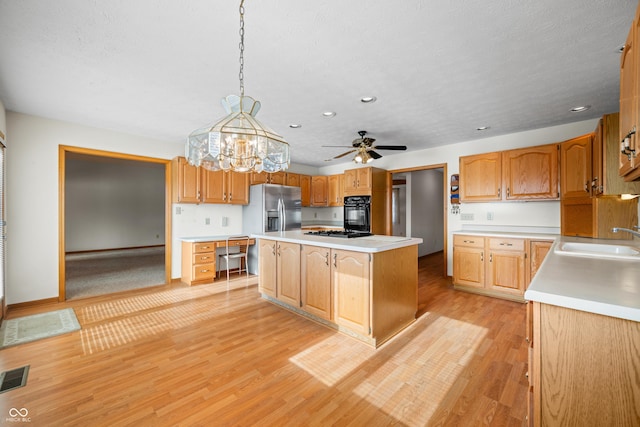 kitchen with a kitchen island, sink, hanging light fixtures, and light hardwood / wood-style flooring