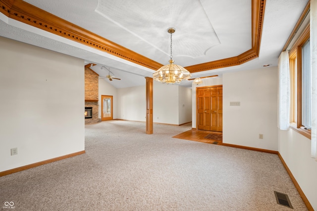 interior space featuring a fireplace, light carpet, ceiling fan with notable chandelier, and a raised ceiling