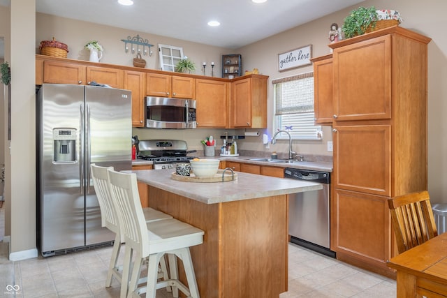 kitchen featuring a breakfast bar, appliances with stainless steel finishes, a center island, and sink