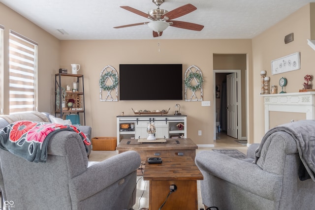 living room featuring ceiling fan, light hardwood / wood-style flooring, and a textured ceiling