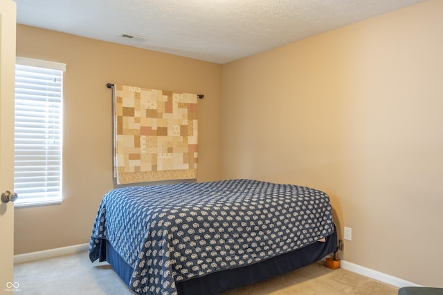 carpeted bedroom featuring multiple windows and a textured ceiling