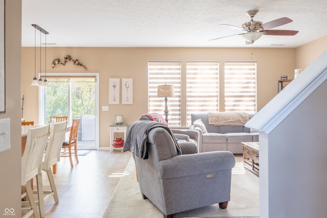 living room featuring ceiling fan and a textured ceiling