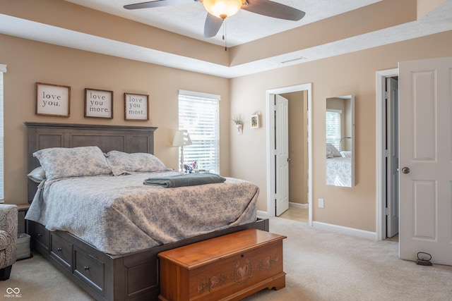 carpeted bedroom featuring a tray ceiling and ceiling fan