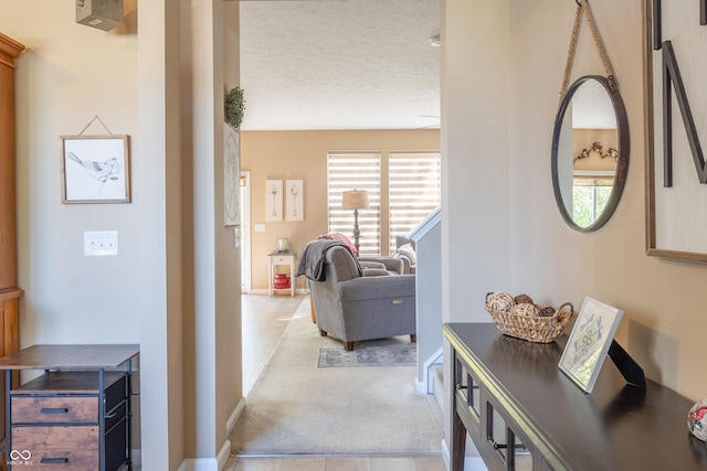 hallway featuring a textured ceiling and light colored carpet