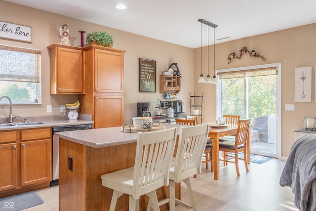 kitchen featuring dishwasher, a center island, sink, decorative light fixtures, and a kitchen bar