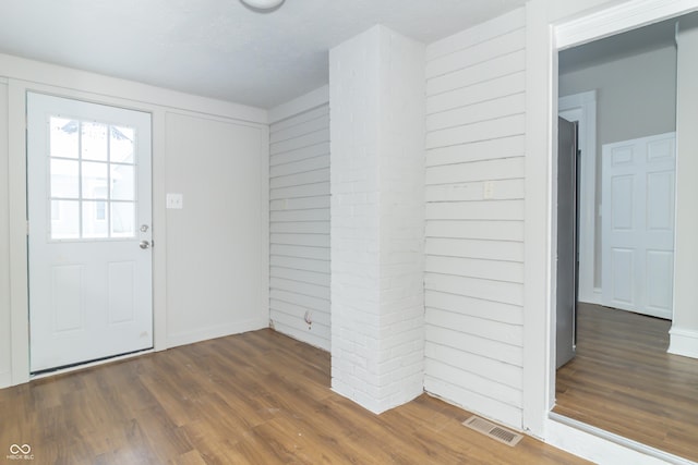 foyer entrance with wood walls and dark wood-type flooring