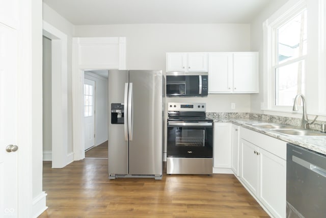 kitchen with light stone countertops, white cabinetry, sink, stainless steel appliances, and dark hardwood / wood-style flooring