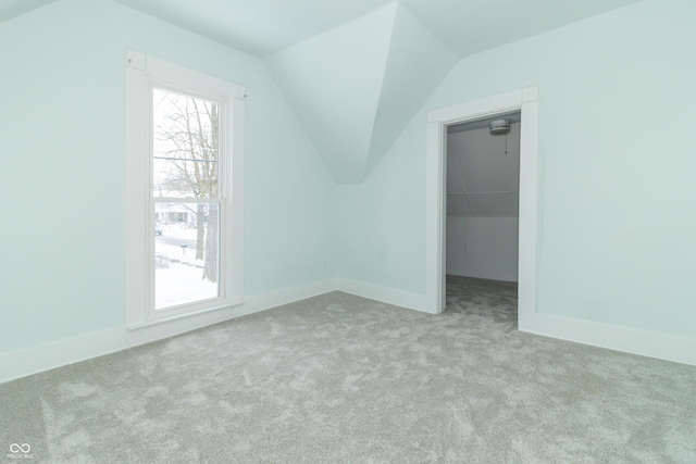 bonus room with light colored carpet and vaulted ceiling