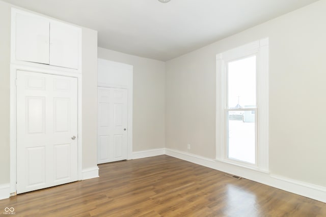 unfurnished bedroom with dark wood-type flooring and multiple windows