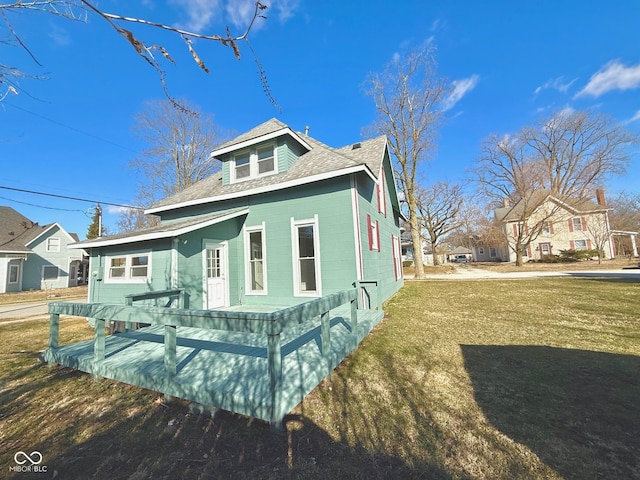 view of side of property with a shingled roof and a yard