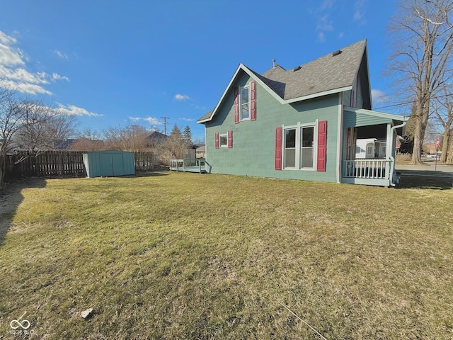 view of home's exterior with an outbuilding, concrete block siding, a lawn, a storage shed, and fence