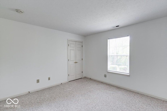 empty room with carpet flooring and a textured ceiling