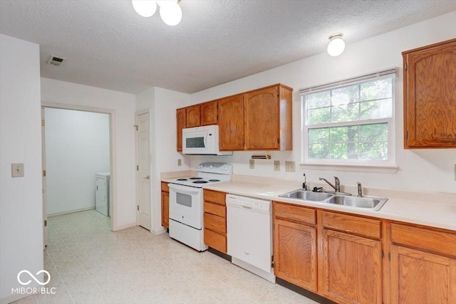 kitchen with a textured ceiling, white appliances, sink, and washer / clothes dryer