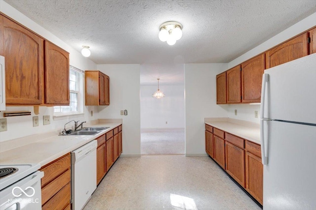 kitchen with pendant lighting, white appliances, a textured ceiling, and sink