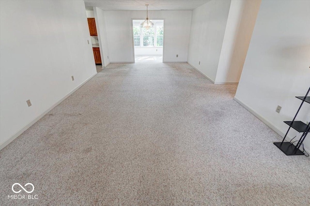 unfurnished room with light colored carpet and a chandelier