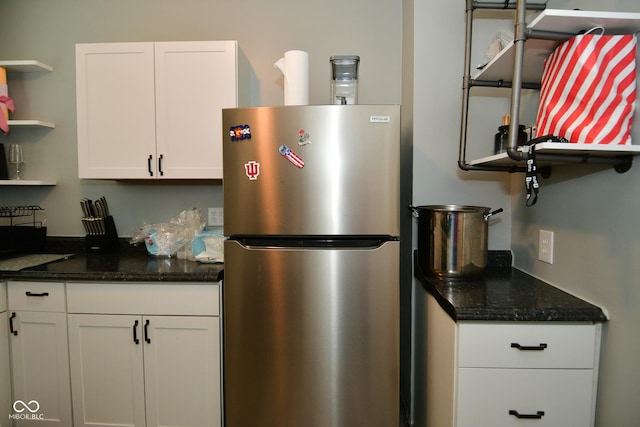 kitchen with white cabinetry, dark stone countertops, and stainless steel fridge