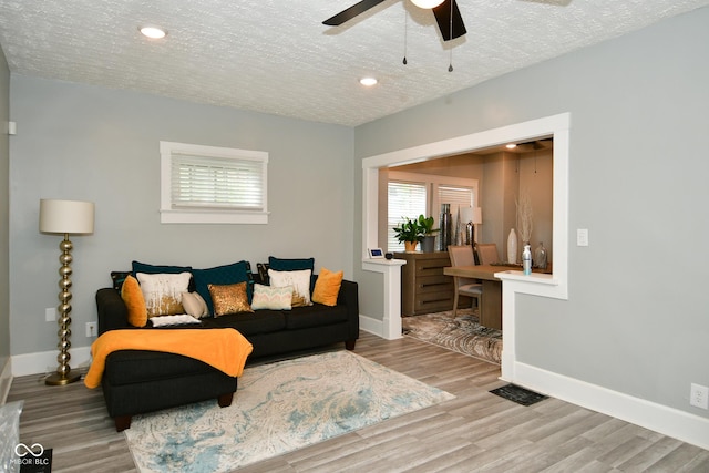 living room featuring a textured ceiling, light hardwood / wood-style flooring, ceiling fan, and a healthy amount of sunlight