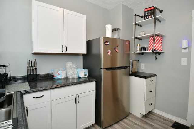 kitchen with white cabinets, light hardwood / wood-style floors, and stainless steel refrigerator