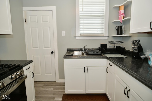 kitchen featuring light wood-type flooring, white cabinetry, sink, and stainless steel stove